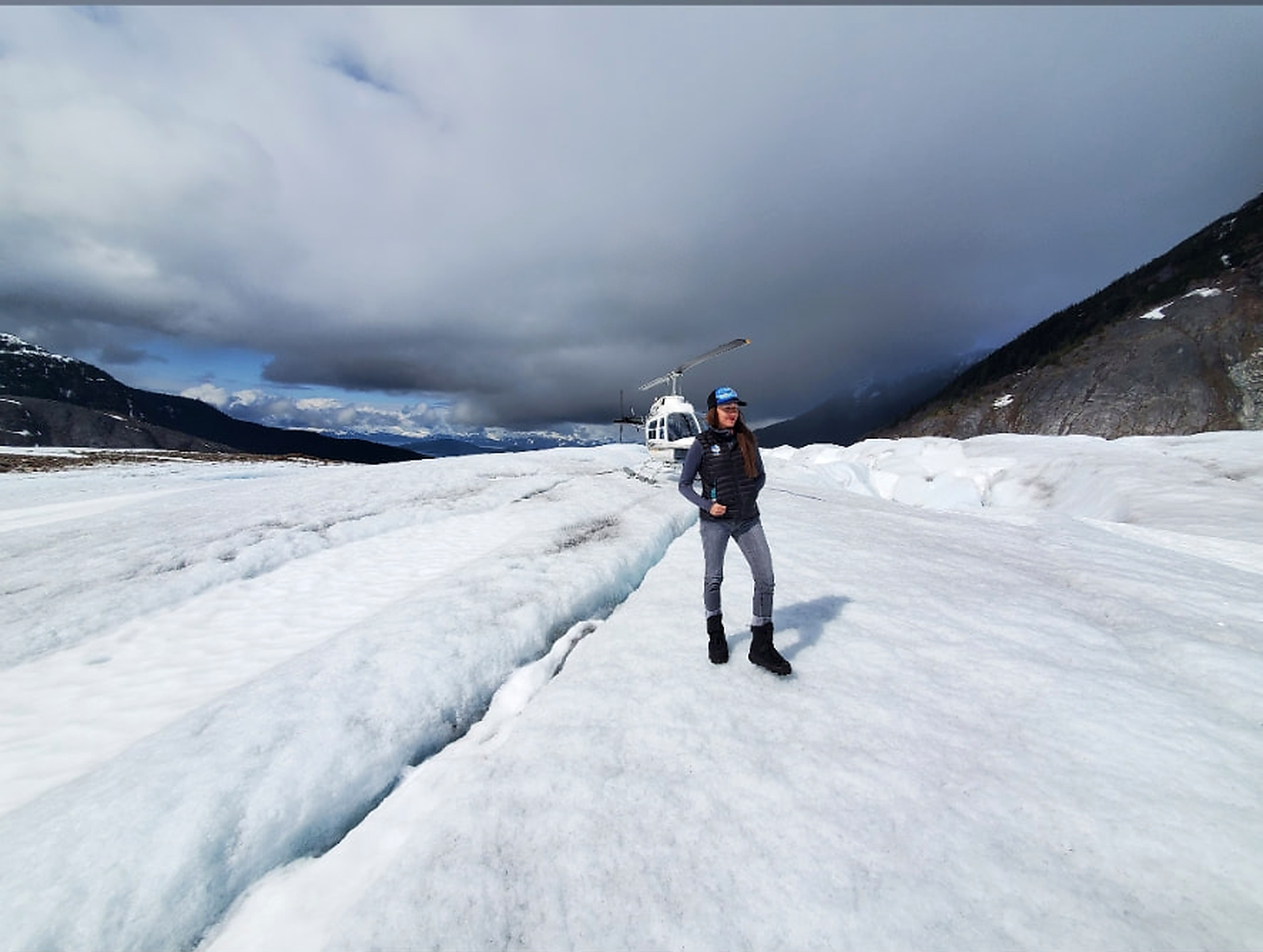Liz Galloway standing beside a helicopter on a glacier